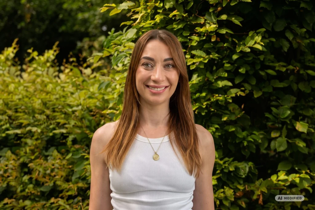 Luisa Sprung, Beraterin und Trainerin bei HLP Consulting, vor einer grünen Hecke – Bild mit KI bearbeitet